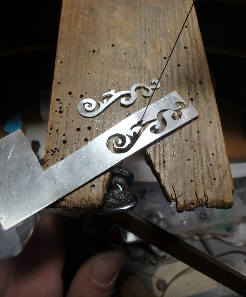 A saw cutting out a design in sterling silver